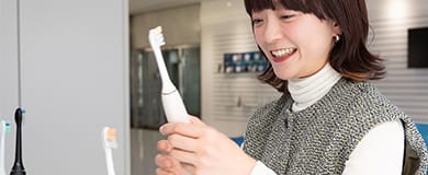 ブログ記事サムネイル。女性が電動歯ブラシを手に持っている様子。