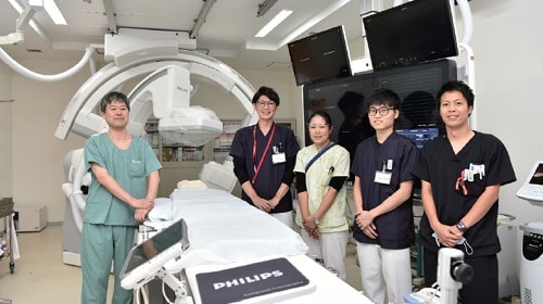 Group of doctors and operators posing for a picture in front of a machine